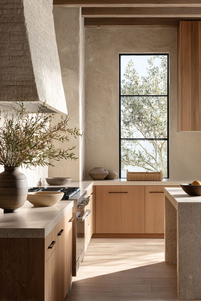 warm wood kitchen cabinets with plaster walls stone countertops and natural light in organic modern kitchen design